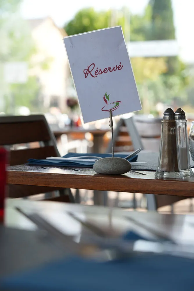 Un carton « Réservé » posé sur une table de la terrasse ombragée